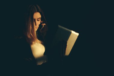 Bir cep telefonu bir karanlık ışık ile yatak odasında yatağın üstüne oturan ağıt tutmak tek üzücü teen