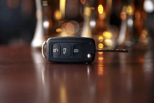 Drinking and driving concept. Car key on a wooden table, pub