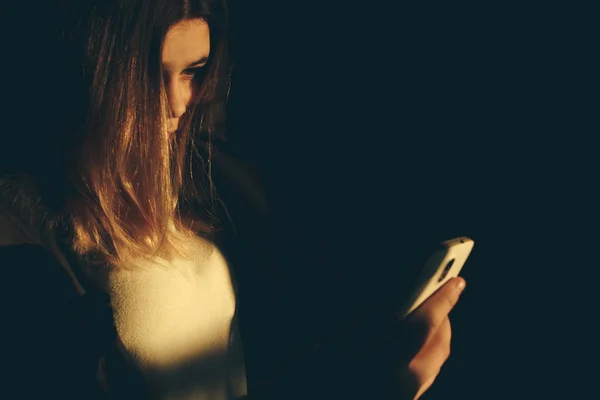 Chica adolescente excesivamente sentado en el teléfono en casa. él es víctima de acoso en línea acosador redes sociales - Imagen — Foto de Stock