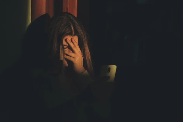 Chica adolescente excesivamente sentado en el teléfono en casa. él es víctima de acoso en línea acosador redes sociales - Imagen — Foto de Stock