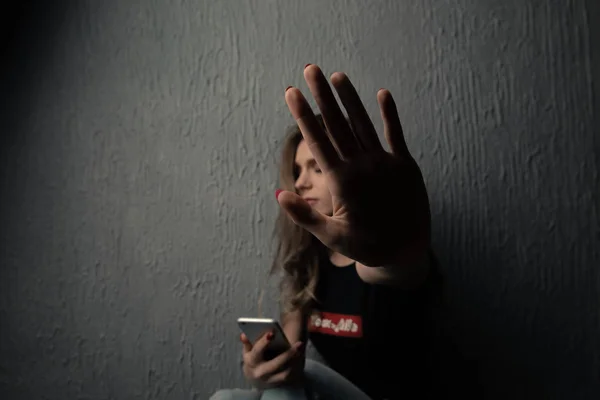 Único adolescente triste segurando um telefone celular lamentando sentado na cama em seu quarto com uma luz escura no fundo — Fotografia de Stock