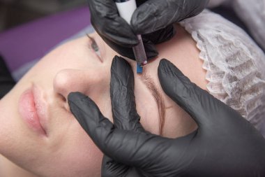 Kalıcı makyaj kaşları için. Microblading kaş. Şevval özçelik güzellik kadın yüzü için kaş dövme yapıyor. Güzel genç kız bir güzellik