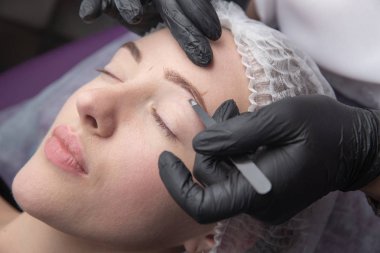 Genç kadın koparma kaşları cımbız ile kapatmak