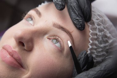 Genç kadın koparma kaşları cımbız ile kapatmak