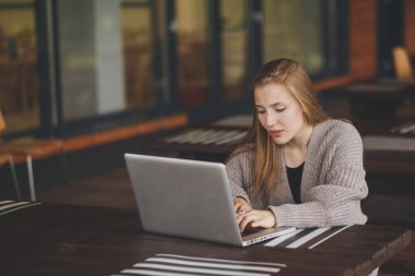 Bir dizüstü bilgisayar ile bir kahve dükkanında çalışan güzel çekici kız