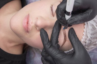 Kalıcı makyaj kaşları için. Microblading kaş. Şevval özçelik güzellik kadın yüzü için kaş dövme yapıyor. Güzel genç kız bir güzellik