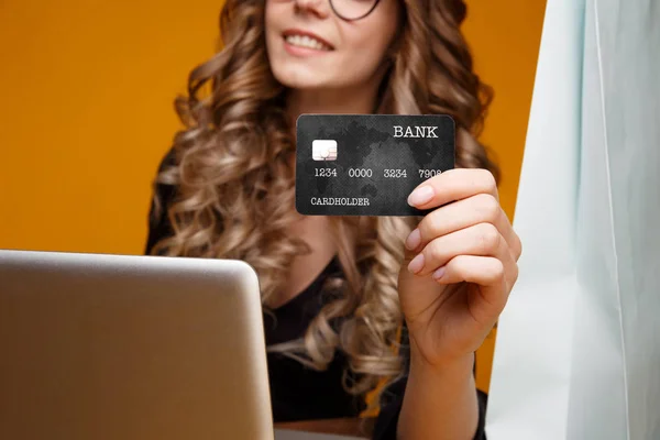 Słodkie uśmiechnięte dziewczyny za pomocą jej laptopa i kartą kredytową za zakupy online, ładny Kobieta w czarnej sukience gospodarstwa czarne karty — Zdjęcie stockowe