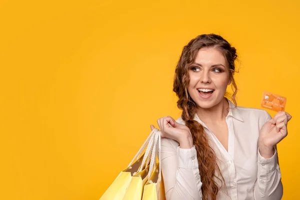 Portrét šťastný milá dívka s kudrnatými vlasy drží tašky a kreditní karty po nakupování — Stock fotografie