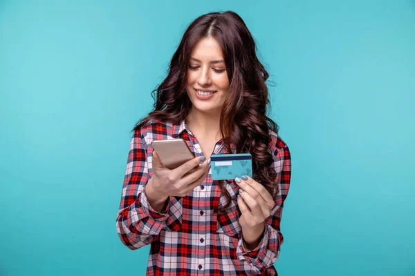 Panienka na białym tle nad niebieskim tle przy użyciu telefonu komórkowego z posiadania karty kredytowej. — Zdjęcie stockowe