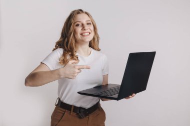 Dizüstü bilgisayar tutarak ve başarı üzerine izole kutlama bir heyecanlı genç sarışın kız portresi