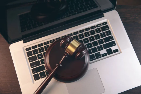 Gavel with books and scales on brown background