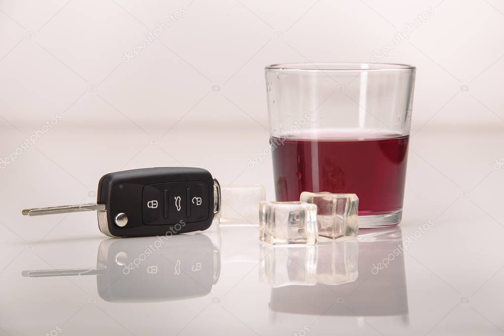 A shot of whiskey and a set of car keys on a white