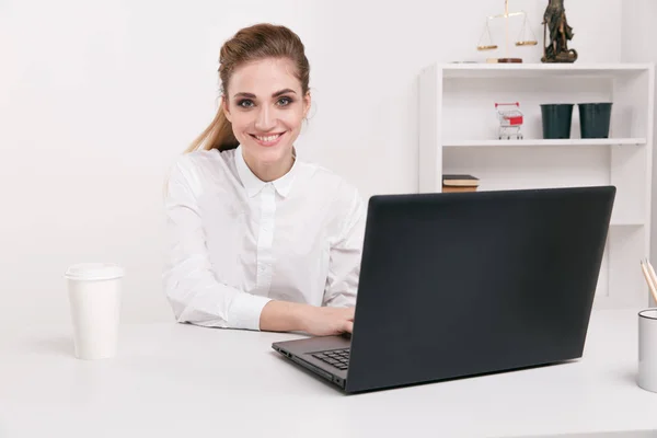 Jeune femme d'affaires en chemisier blanc assis dans un bureau. Employé de bureau assis devant un ordinateur noir. Café au bureau . — Photo