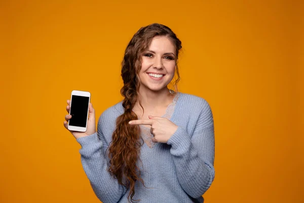 블루 스웨터 미소 하 고 그녀의 전화를 들고 있는 예쁜 여자 — 스톡 사진