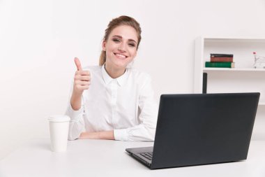 Beyaz bir bluz bir ofiste oturan genç işkadını. Ofis çalışanı siyah bilgisayar infront oturuyor. Kahve Office