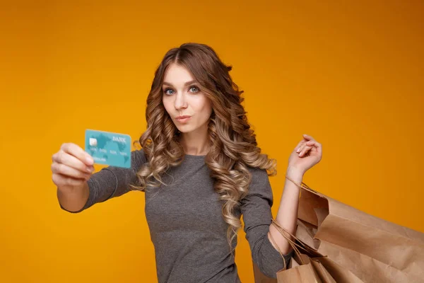 Young beautiful woman holding shopping bags and a credit card — Stock Photo, Image