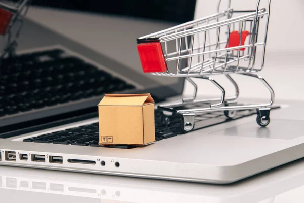 Cajas en y carro en un ordenador portátil de compras en línea es una forma de comercio electrónico que permite a los consumidores comprar directamente bienes de un vendedor más — Foto de Stock