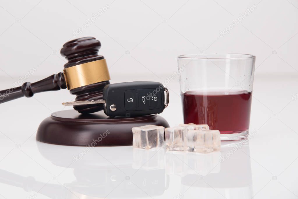 A shot of whiskey and a set of car keys on a white