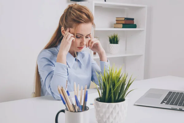 Joven chica de oficina sentada en su lugar de trabajo sintiéndose mal. La mujer tiene dolor de cabeza. . — Foto de Stock