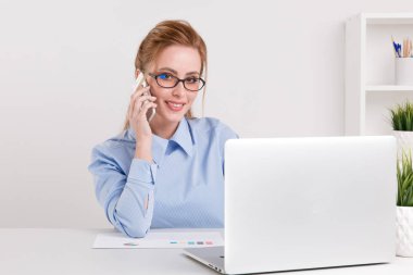 Ofiste çalışan mutlu çıktıktan güzel kadın. Yakışıklı işkadını telefonu konuşurken bir gözlük ve mavi bluz