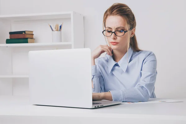 Poważne kobietę w okularach pracę swojego laptopa. Biuro kobieta wygląda zmęczony. — Zdjęcie stockowe