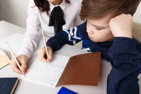 Mutter und ihr Sohn bei den Hausaufgaben im weißen Zimmer. Hausaufgaben in einer Notiz. — Stockfoto