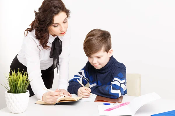 Kadın öğretmen genç çocuk ödevini yapmak için yardımcı olur. Birlikte ödev. — Stok fotoğraf