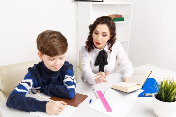Tutor and student sitting in the white room and doing tasks for lessons. — Stock Photo, Image