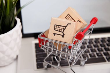 Birçok kağıt kutular bir dizüstü bilgisayar klavye üzerinde küçük bir alışveriş arabası. Bu tüketicilerin online alışveriş hakkındaki kavramları şeyler doğrudan doğruya--dan onların ev ya da ofis sadece birkaç tıklama ile web tarayıcısı kullanarak satın alabilirsiniz.