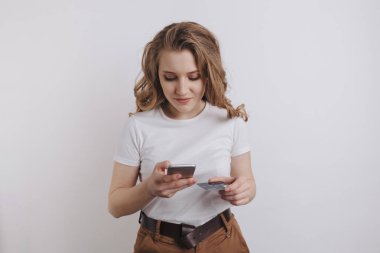 Mutlu güzel kız onun telefon ve turuncu kredi kartı ile online alışveriş yapma.