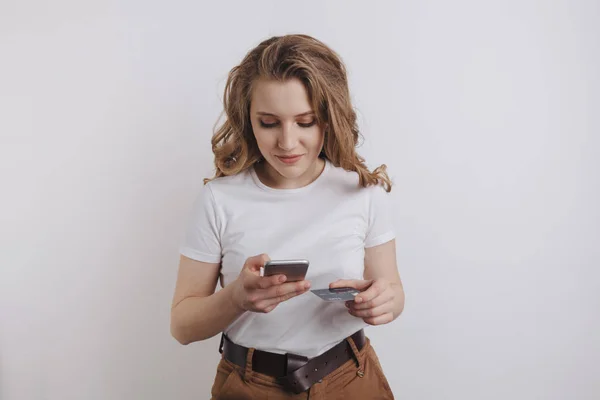 Gelukkig mooi meisje waardoor online winkelen met haar telefoon en oranje credit card. — Stockfoto