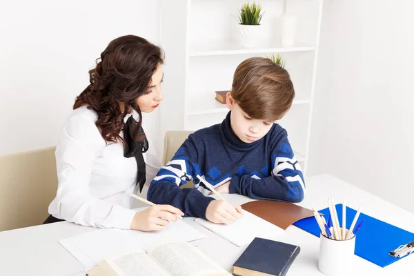 Nauczycielka pomaga teen chłopiec, aby zrobić swoją pracę domową. Wykonując zadania razem. — Zdjęcie stockowe
