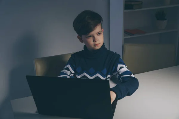 Foto van mooie jongen in trui zit infront van de computer huiswerk. — Stockfoto