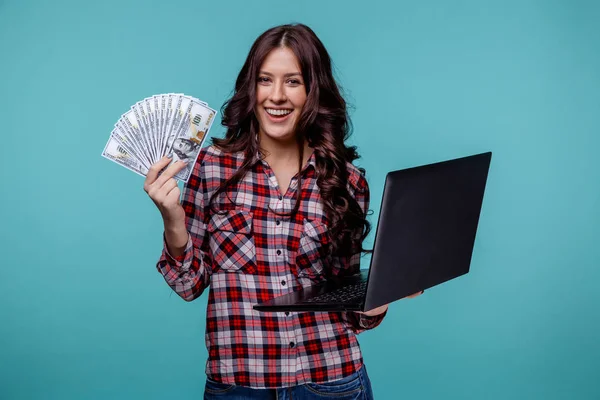 Ładne kobiety holdina pieniądze i laptopa właśnie do aparatu na białym tle niebieski. — Zdjęcie stockowe