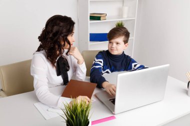 Genç öğretmen çocukla bir bilgisayarda ödev. Öğretmen yardım.