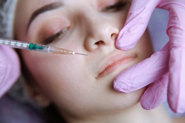 Doktor güzellik uzmanı sıkma ve güzel, genç bir kadının bir güzellik, yüz cilt kırışıklıkları yumuşatma için gençleştirici yüz enjeksiyonları yordam bulunur