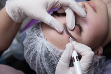 Kalıcı makyaj kaşları için. Microblading kaş. Şevval özçelik güzellik kadın yüzü için kaş dövme yapıyor. Güzel genç kız bir güzellik