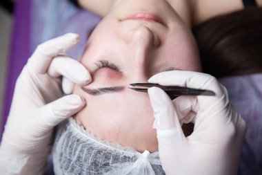 Genç kadın koparma kaşları cımbız ile kapatmak