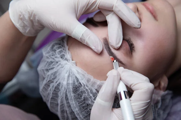 Maquiagem permanente para sobrancelhas. Testa de Microblading. Esteticista fazendo tatuagem de sobrancelha para rosto feminino. Menina bonita em uma beleza — Fotografia de Stock