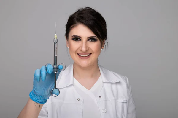 Zbliżenie zdjęcie kobieta dentysty trzymając strzykawkę na białym tle nad szary backgrownd. — Zdjęcie stockowe
