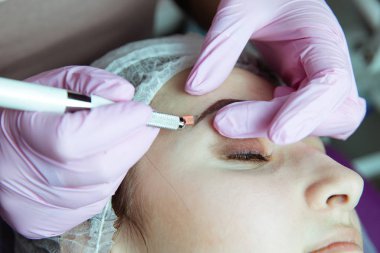 Kalıcı makyaj kaşları için. Microblading kaş. Şevval özçelik güzellik kadın yüzü için kaş dövme yapıyor. Güzel genç kız bir güzellik