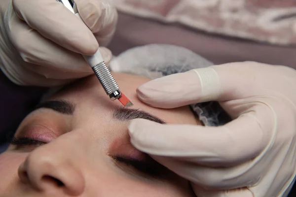 Maquillaje permanente para las cejas. Ceja de Microblading. esteticista haciendo tatuajes de cejas para la cara femenina. Hermosa joven en una belleza —  Fotos de Stock
