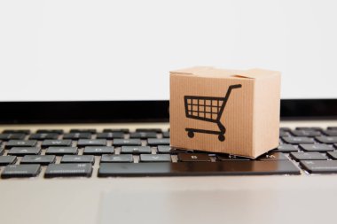Online alışveriş. e-ticaret ve teslimat hizmeti kavramı: kağıt karton bir arabası ya da logo üstünde a laptop klavye trolley, perakendeci siteleri üzerinden gelen müşteriler sipariş şeyler gösteriyor