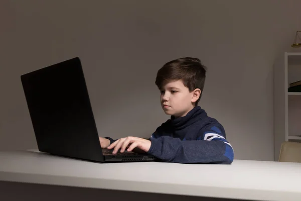 Foto de menino legal em suéter sentado na frente do computador fazendo lição de casa . — Fotografia de Stock