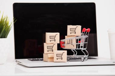 Online alışveriş e-ticaret ve teslimat hizmeti kavramı: kağıt karton ile bir alışveriş sepeti veya logo üstünde a laptop klavye trolley, perakendeci siteler internet üzerinden gelen müşteriler sipariş şeyler gösteriyor