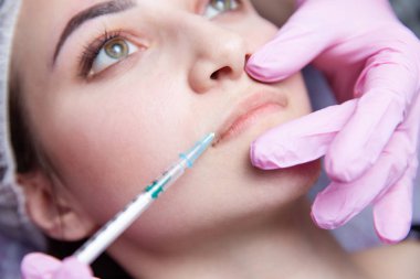 Doktor güzellik uzmanı sıkma ve güzel, genç bir kadının bir güzellik, yüz cilt kırışıklıkları yumuşatma için gençleştirici yüz enjeksiyonları yordam bulunur