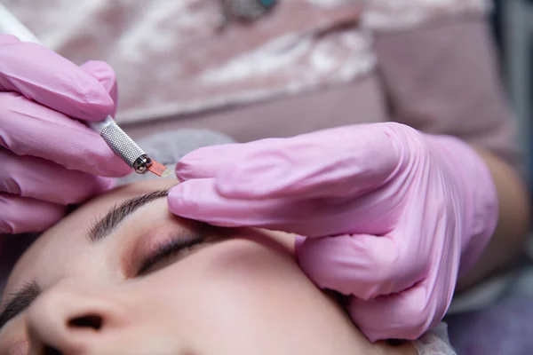 Maquiagem permanente para sobrancelhas. Testa de Microblading. Esteticista fazendo tatuagem de sobrancelha para rosto feminino. Menina bonita em uma beleza — Fotografia de Stock