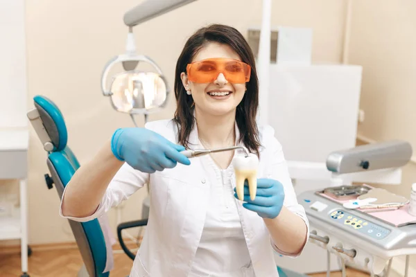 Dentista femminile nella maschera che mostra come fare la limatura dei denti sul modello di dente . — Foto Stock