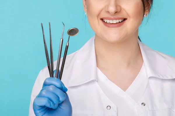 Hermoso dentista morena con herramientas aisladas sobre el fondo azul . —  Fotos de Stock