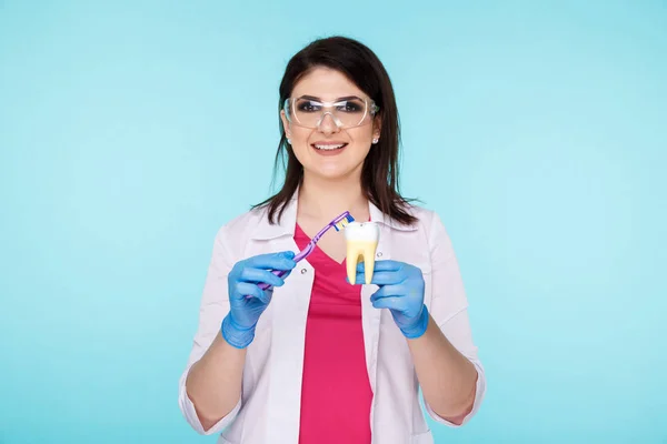 Young dentist showing how to brush your teeth properly isolated over the blue background.